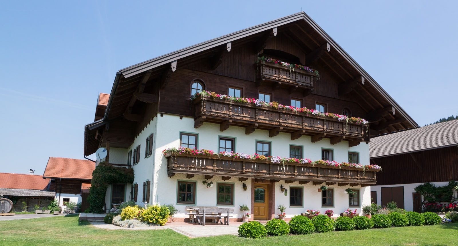 Unser Ferienhof mit blumengeschmückten Holzbalkonen
